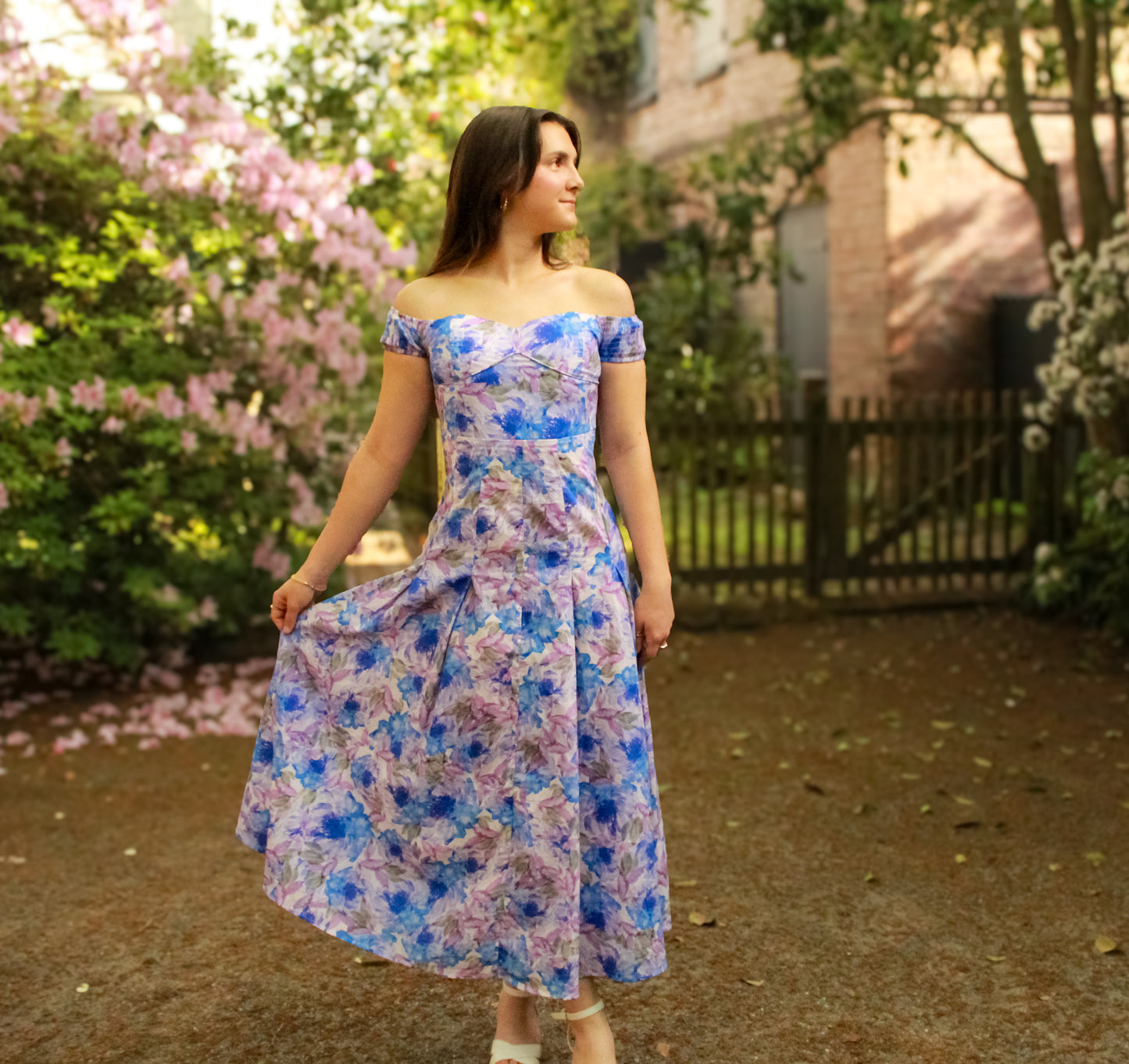 Off-shoulder floral dress in blue and purple, featuring a fitted bodice and flowing skirt, perfect for spring.