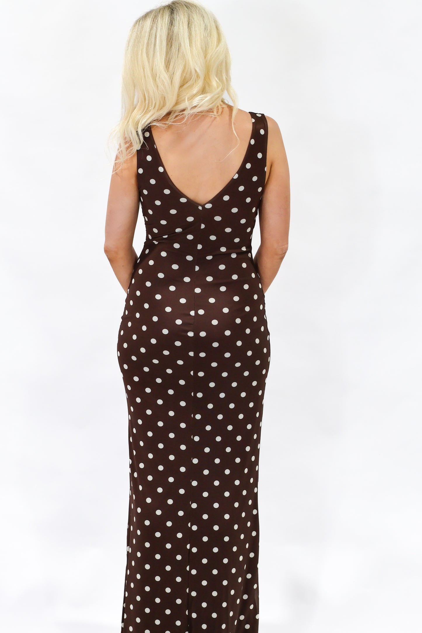 Woman wearing a brown polka dot dress on a white background
