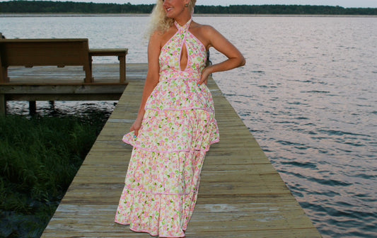 Floral halter maxi dress in pink, featuring a ruffled hem and open back, perfect for summer outings.