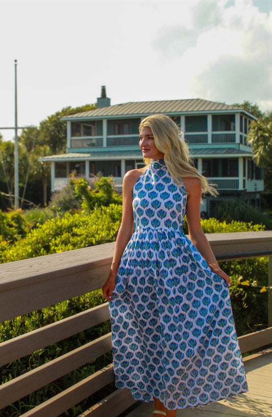 Model wearing a blue and white floral maxi dress with a high neckline and flowing skirt.