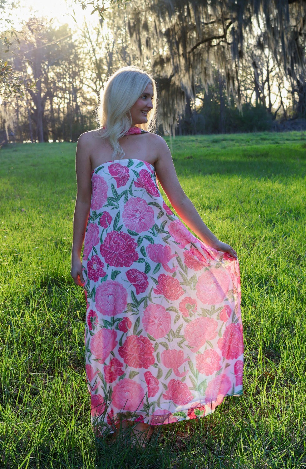 Woman in a pink floral dress standing in a grassy field