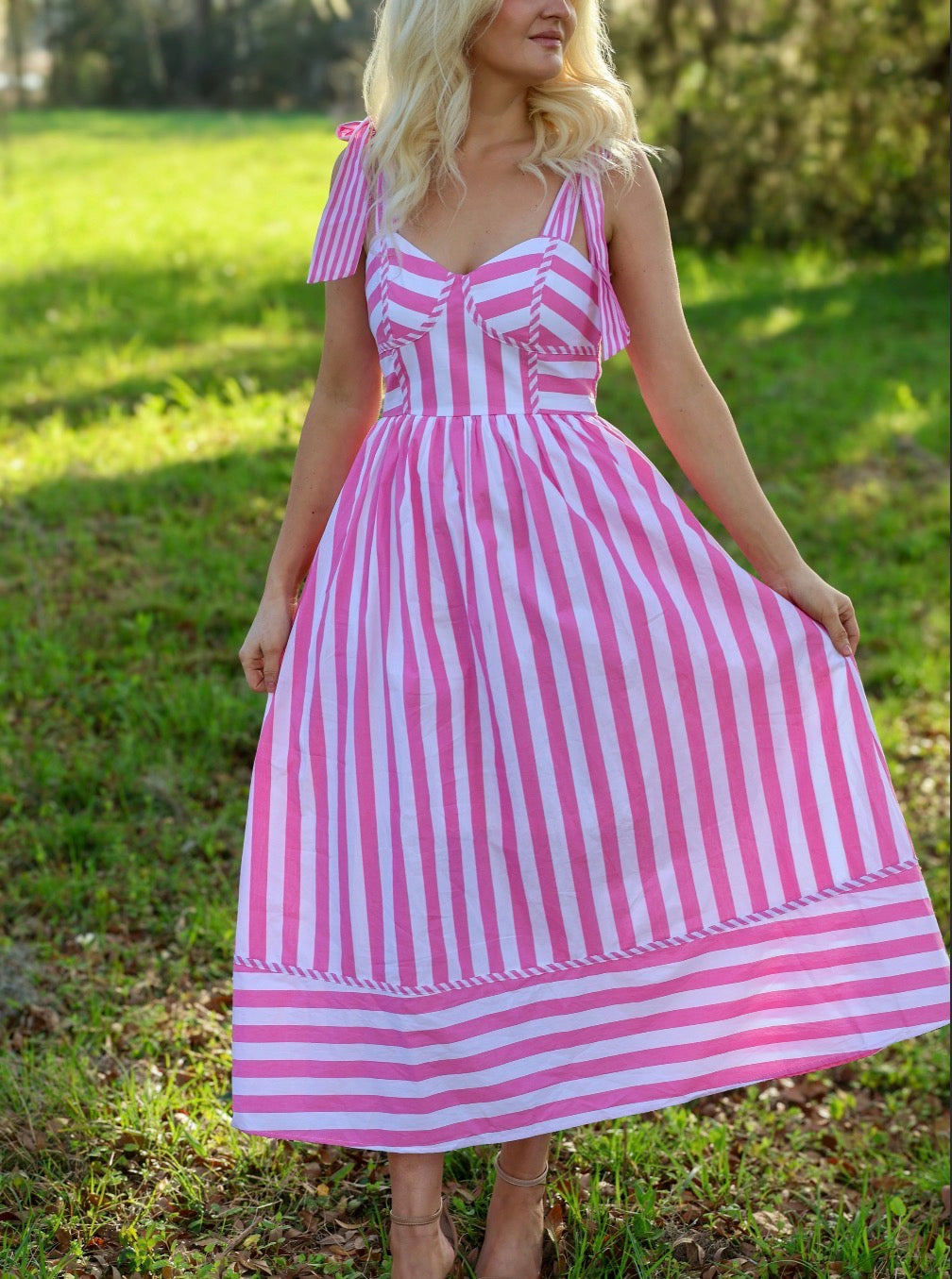 Woman wearing a pink and white striped dress in an outdoor setting