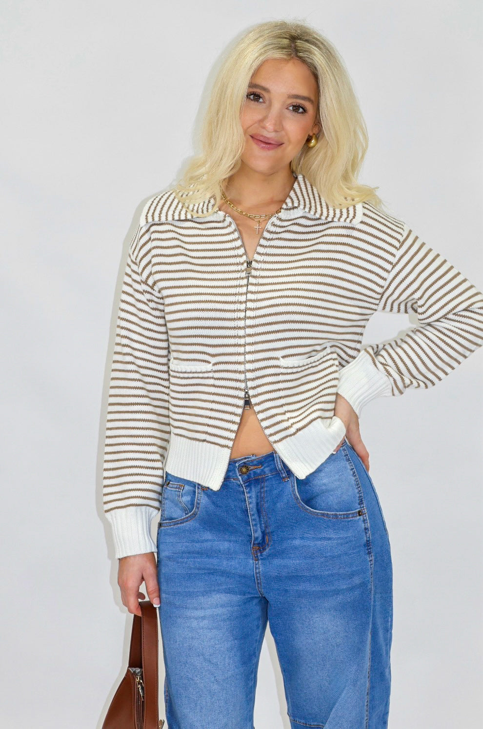 Woman wearing a striped sweater and blue jeans on a plain background