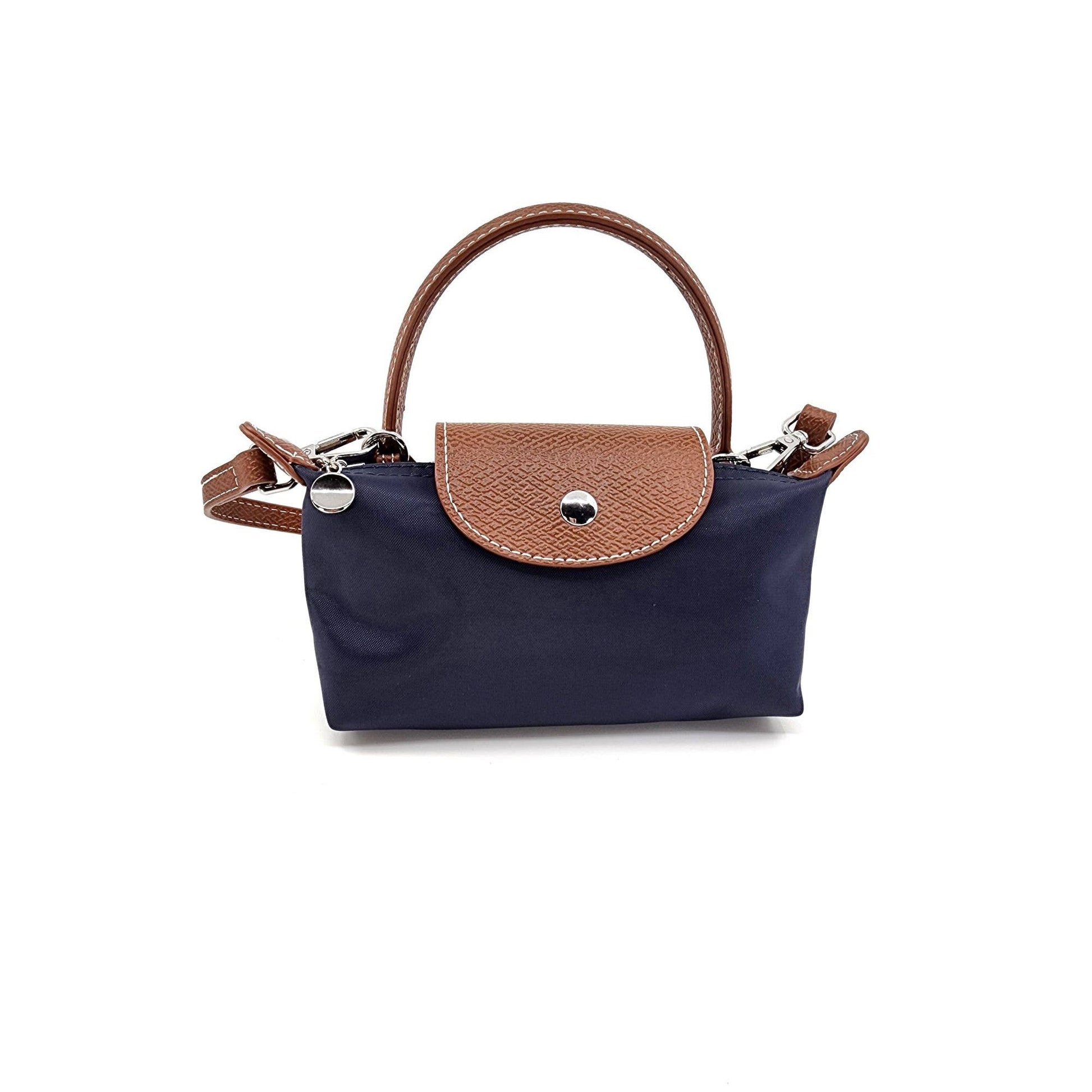 Navy handbag with brown leather handle and flap on a white background